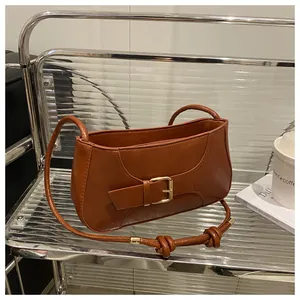 Détail d'un sac cabas en cuir marron montrant une boucle en métal et des nœuds décoratifs