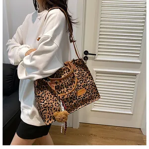 Detail of leopard print canvas tote bag featuring brown handles and cute bear charm