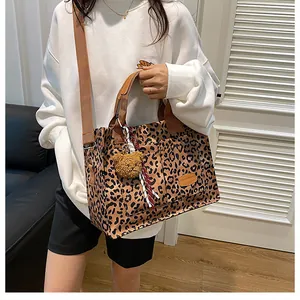 Detail of leopard print tote with brown straps, exterior pocket and teddy bear charm