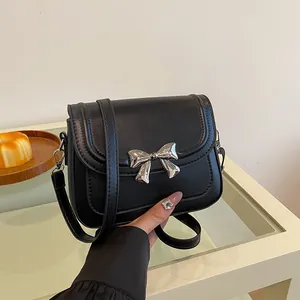 Elegante borsa a tracolla nera con fiocco argento e trama in pelle PU in un ambiente accogliente