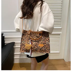 Close-up of leopard print canvas tote bag with brown leather strap and plush bear charm