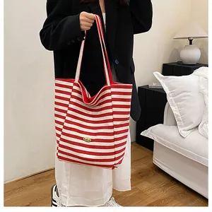 Détail du sac fourre-tout rayé rouge et blanc avec logo métallique doré et large bandoulière