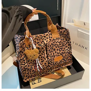 Detail of leopard print tote bag with functional pockets and plush bear charm
