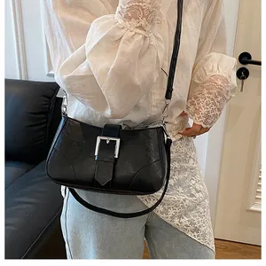 Detail of a black glossy leather underarm bag with a stylish silver square buckle
