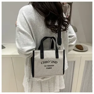 Détail du sac cabas en toile avec bordure en cuir noir et bandoulière réglable