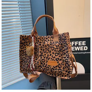 Close-up of leopard print canvas tote bag featuring outer pockets and a plush bear charm