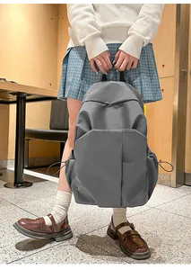Détail d'un sac à dos gris minimaliste avec poches latérales à cordon et bretelles larges
