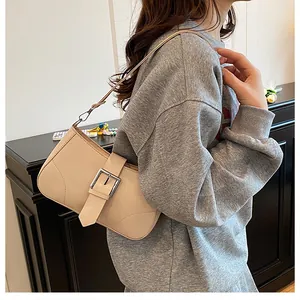 Detail view of the beige underarm bag showing the silver square buckle and leather strap