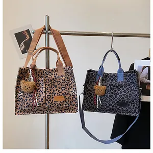 Detail of leopard print canvas tote bag featuring adjustable strap and bear pendant