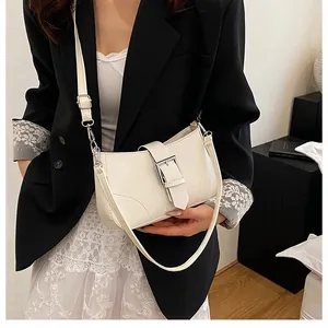 Detail of a minimalist off-white shoulder bag with silver buckle and adjustable strap