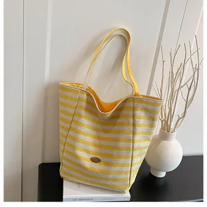 Vue détaillée du sac cabas en maille rayé jaune et blanc avec emblème métallique chic