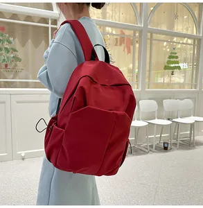 Détail sac à dos en toile rouge foncé avec poche latérale et bretelles larges