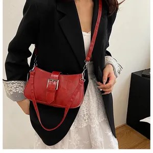 Detail of red leather shoulder bag with vintage silver buckle and adjustable strap