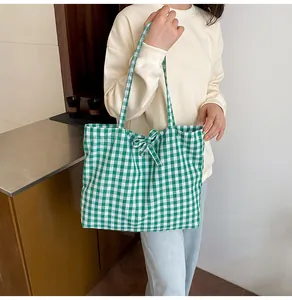 Detail of green and white gingham canvas tote bag with decorative bow on a female model