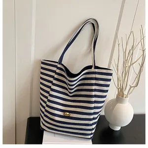 Détail du sac cabas rayé bleu avec badge en métal handmade et texture toile robuste