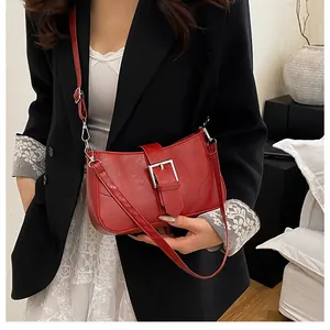 Detail of red French retro shoulder bag showing metallic silver buckle and leather texture