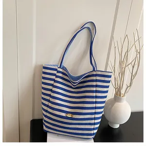 Détail de la plaque dorée handmade sur le sac cabas à rayures bleues et blanches