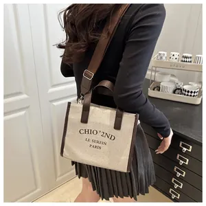 Vue détaillée du sac cabas en toile beige avec finitions en cuir marron et bandoulière