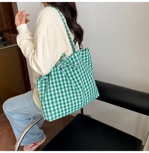 Detail of green and white plaid fabric tote bag featuring a decorative bow tie accent