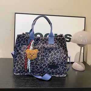 Leopard print canvas tote bag with purple handles, shoulder strap and plush bear charm