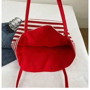 Détail de la vue de dessus du cabas en toile rayée montrant la doublure rouge et la capacité
