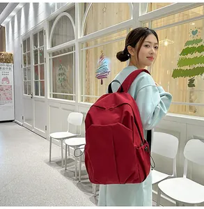 Vue latérale détaillée d'un grand sac à dos rouge minimaliste porté par un mannequin en décor
