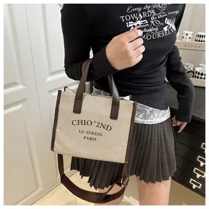 Détail du sac cabas en toile beige avec anses en cuir marron et large bandoulière réglable