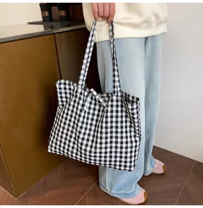 Detailed view of large black and white checkered canvas tote bag with long carry straps