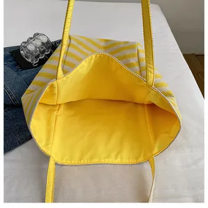 Détail du grand sac cabas en maille rayée avec doublure intérieure jaune et anses