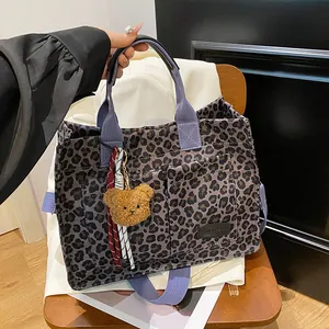 Leopard print canvas tote bag with purple straps and cute bear charm in lifestyle setting
