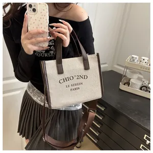 Détail du sac cabas en toile avec anses en cuir marron et bandoulière réglable