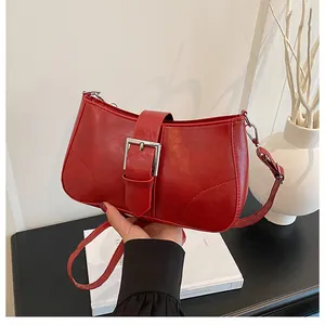 Detail of red vintage underarm bag with silver square buckle and textured leather finish