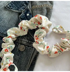 Detail of floral scrunchie in beige with small red flowers on a denim fabric background