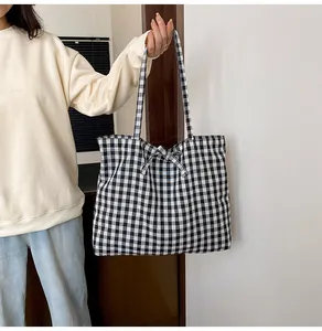 Detail of a black and white gingham tote bag with a decorative bow and shoulder straps