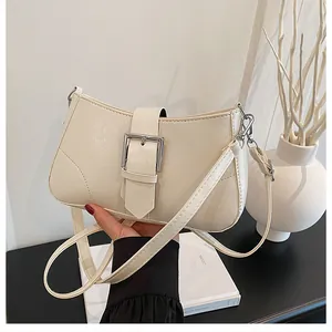 Detail of cream leather shoulder bag showing the silver buckle and fine grain texture