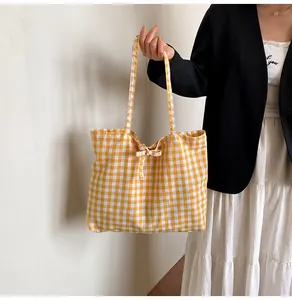 Detail of yellow and white plaid canvas tote bag with decorative shoulder strap bows