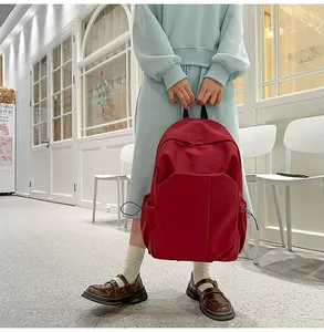 Détail du sac à dos rouge minimaliste avec poches latérales à cordon et grande capacité