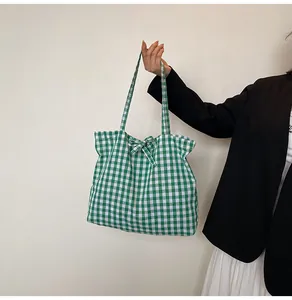 Detailed view of a green and white plaid tote bag with a decorative bow knot