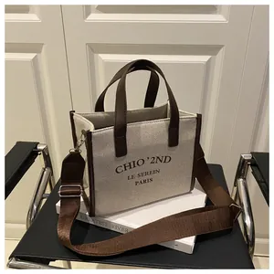 Détail du sac bandoulière en toile avec bordure en cuir marron et sangle ajustable