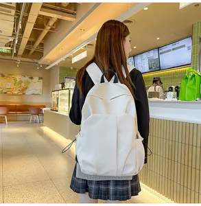 Détail du sac à dos en cuir blanc avec coutures géométriques et poche latérale à cordon