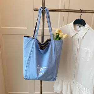 Sac fourre-tout bleu avec imprimé beyou et doublure rayée bleue suspendu à un cintre