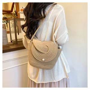 Detail of hand-woven beige mini bag with spiral shell pattern and large pearl clasp