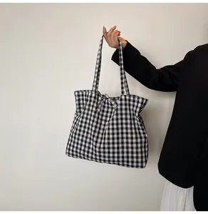 Detail of classic black and white gingham tote bag with stylish bow tie and canvas texture