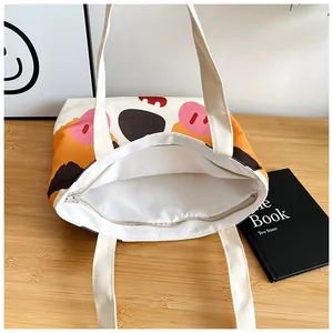 Detail view of canvas tote bag with cartoon print, zipper closure and white lining