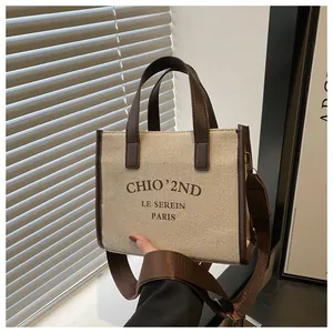 Détail du sac cabas en toile beige avec bordure en cuir marron et bandoulière réglable