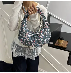 Detail of floral dumpling bag with ruched handle, bow drawstring and zipper closure