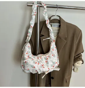 Detailed view of floral dumpling bag featuring red flower prints and ribbon decorations