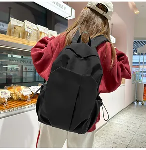 Détail d'un grand sac à dos en toile noire avec plusieurs poches et cordons de serrage