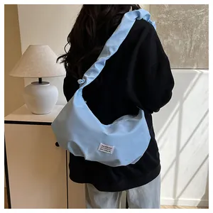 Vue latérale du sac nuage bleu clair avec bandoulière plissée et étiquette mode