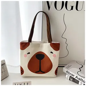 Detail of canvas tote bag featuring cute cartoon dog print and brown webbing straps